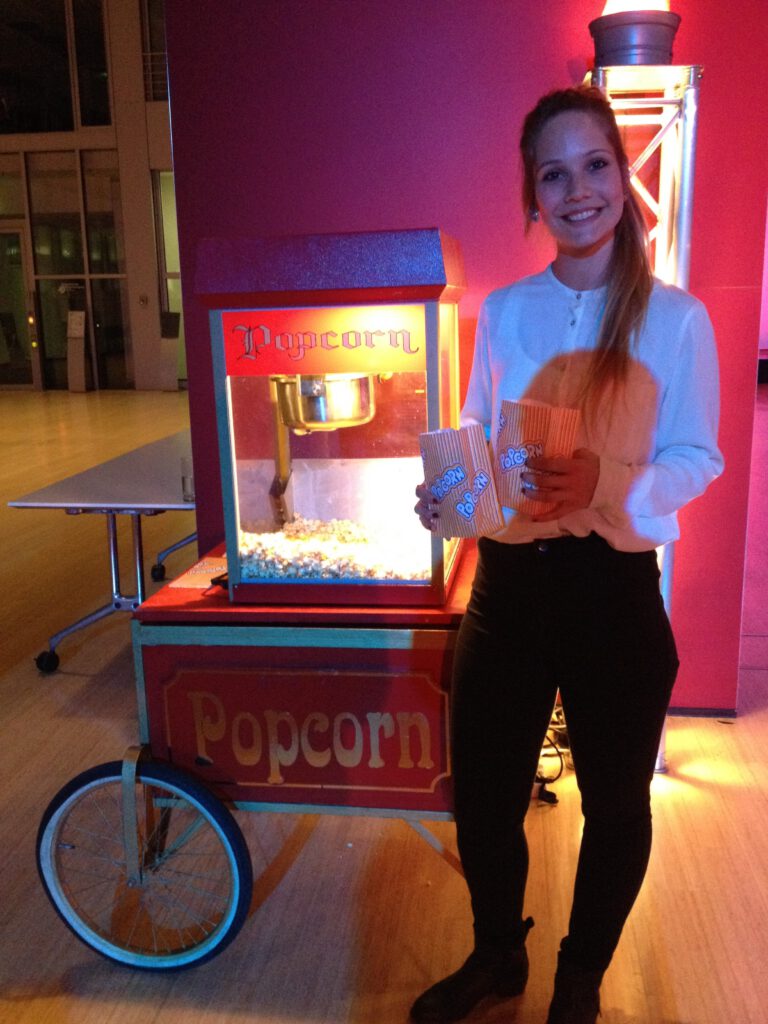 Popcorn mit Hostess vor einer Popkorn Maschine.